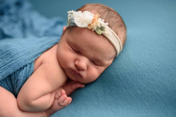 istock Cute newborn girl sleeping on a blue background in a blue wrapping. 1217363438