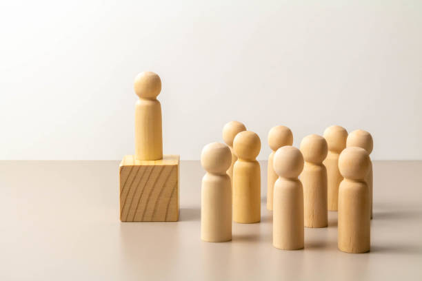 istock Wooden figure on cube, other figures around on floor 1217365803