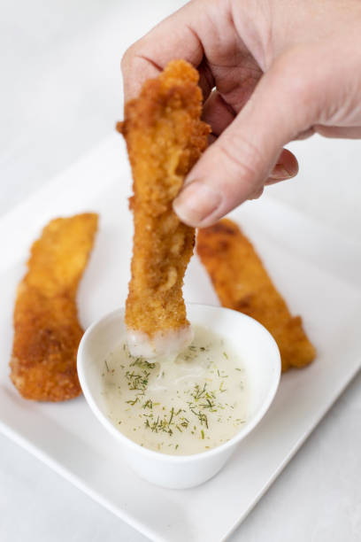istock Hand dip fried chicken in dill sauce above white marble table background 1217366311