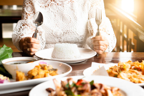 repas heureux de famille avec la nourriture pleine sur la main de mère aînée asiatique de table de main, couteau, riz sur l’assiette - table. profitez d’un véritable repas thaïlandais sain exotique authentique avec son enfant en vacances - bon appetite photos et images de collection