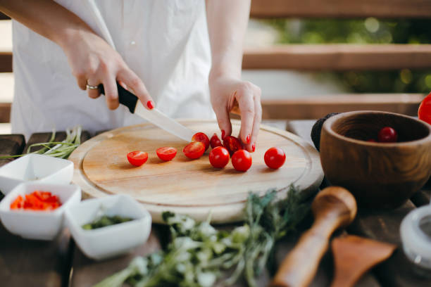istock Woman's hands cutting cherry tomatoes on a wooden plate. Making guacamole 1217370047