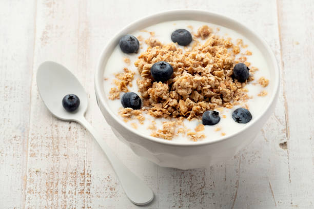 Muesli with yoghurt in a bowl on white wooden background stock photo
