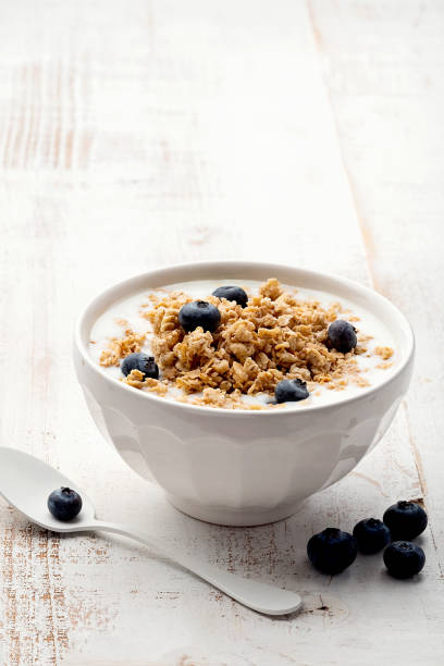 Muesli with yoghurt in a bowl on white wooden background Muesli with yoghurt in a bowl on white wooden background muesli stock pictures, royalty-free photos & images