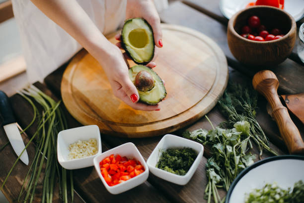istock Woman's hands cutting avocado in half. Two avocado halves ready for guacamole making 1217370604