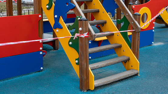 Playground staircase wrapped in barrier tape closeup. Prohibition of outdoor walks with children, prevention of infection with the coronavirus covid-19 virus. Bright colorful reporting