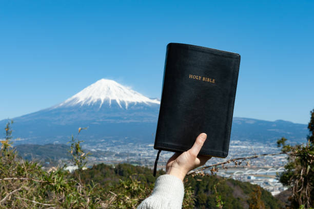 raised hand holding the holy bible. background with aerial view of fuji city and mount fuji with blue sky on a beautiful winter morning. - god freedom arms raised high angle view imagens e fotografias de stock
