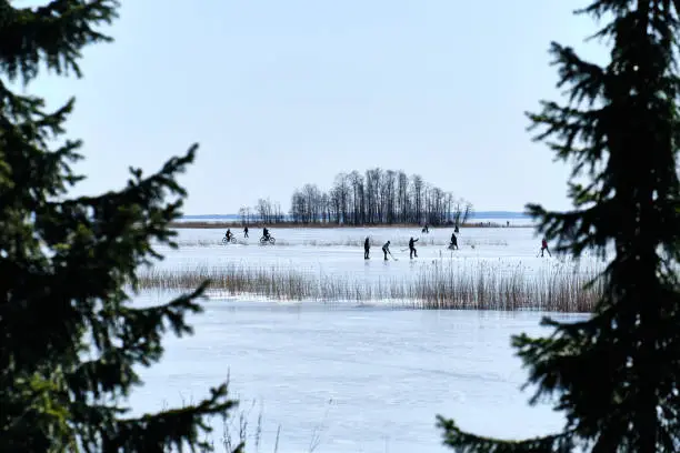 Photo of Weekend on the ice-covered lake in Joensuu, Finland. People ride bikes, play hockey, walking on the lake ice.