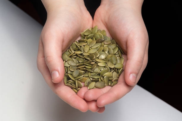 istock Pumpkin seeds in hand on white background 1217373929