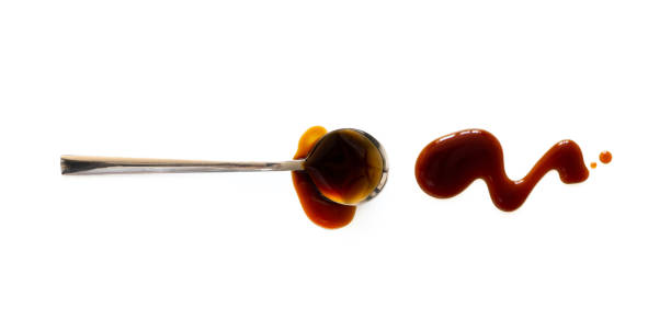 Spoon with teriyaki and soy sauce splash isolated on white background, top view. Close-up seasoning and dip stock photo