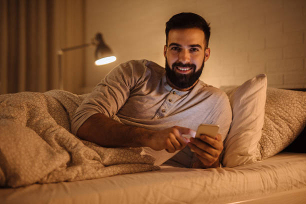 istock Handsome bearded man using phone in the bed at night 1217377528