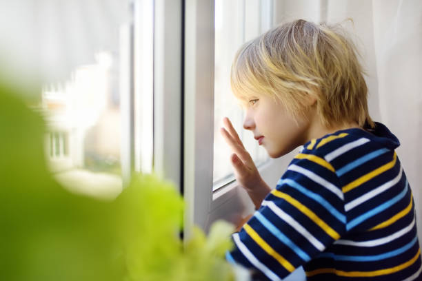 istock Sad little boy looking into window during coronavirus pandemic. Child boring without communication and walking. Stay at home while quarantine. 1217377956