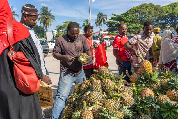 африканец продает тропические фрукты на местном рынке уличной еды на острове занзибар, танзания, восточная африка - africa agriculture zanzibar industry стоковые фото и изображения