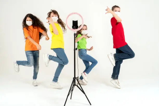 Photo of Children dance positively in medical masks. The concept of distance learning during a pandemic. Positive. Movement and sport