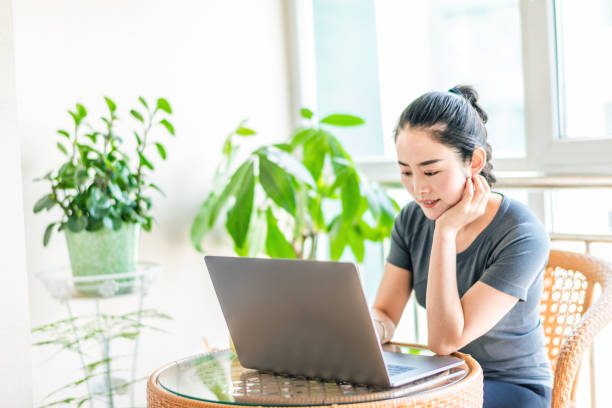 istock Asian young woman using computer in living room 1217381395