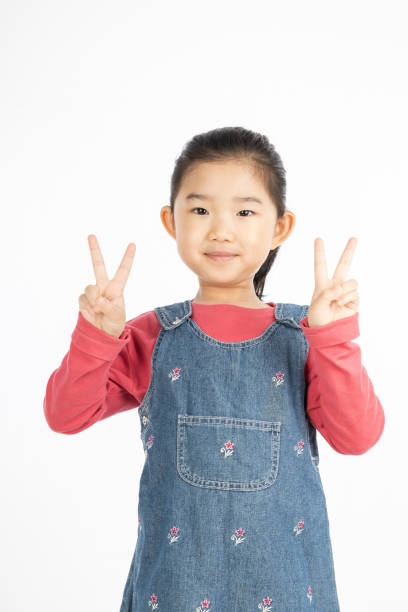 istock Little girl making V shape gesture on White Background 1217381715
