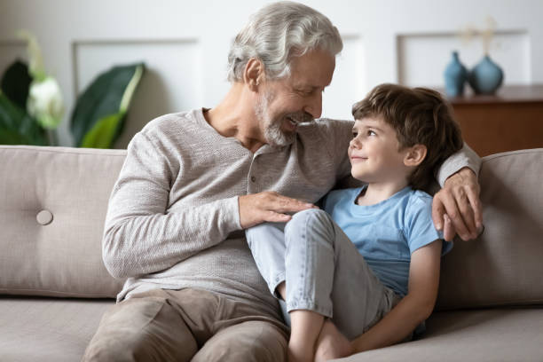 amorevole nonno anziano goditi il fine settimana con il nipotino - whispering grandparent child grandfather foto e immagini stock