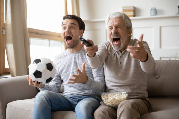 istock Excited young man have fun watching game with senior father 1217386246