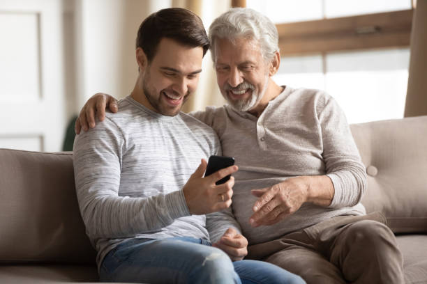istock Overjoyed senior dad and adult son using have fun smartphone 1217386285