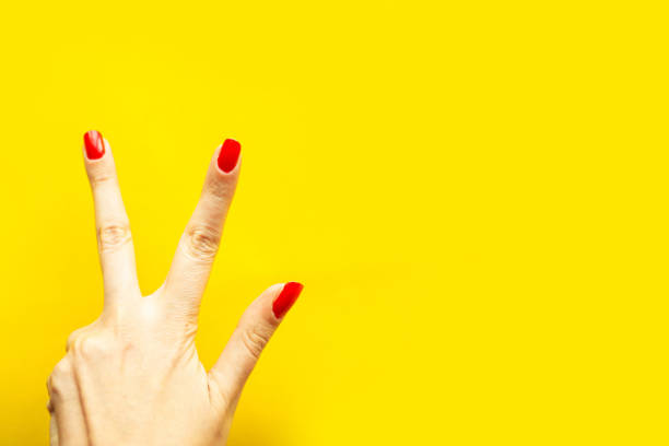 istock Woman's hand shows the victory gesture over bright yellow background. Minimal concept. Copy space for the text 1217386437