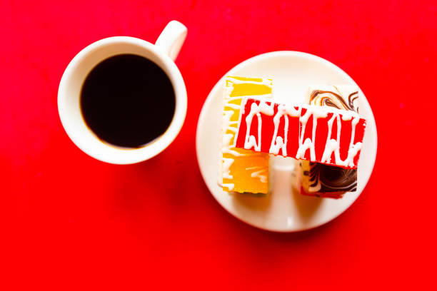 Delicious color cakes on a plate and coffee cup, top view. Bright red background, minimal concept.