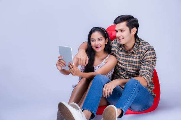 молодая пара на белом фоне - фондовые изображения - digital tablet indian ethnicity young couple computer стоковые фото и изображения