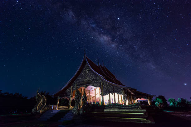 vista notturna di wat sirindhorn wararam phu prao, bagliore nel tempio oscuro sotto la via lattea, ubon ratchathani, thailandia - luminant foto e immagini stock