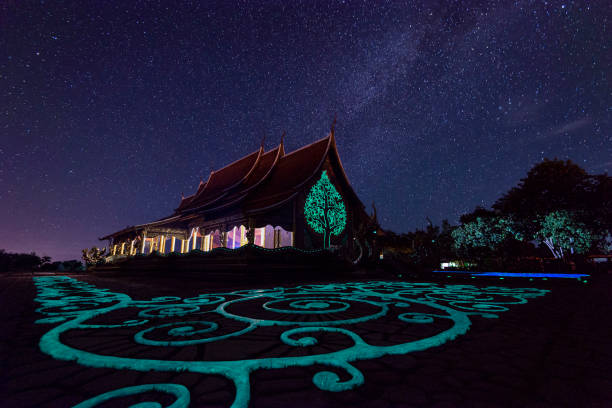 vista notturna di wat sirindhorn wararam phu prao, bagliore nel tempio oscuro sotto la via lattea, ubon ratchathani, thailandia - luminant foto e immagini stock