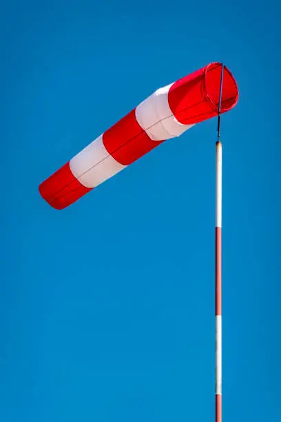 Airport windsock on clear blue sky background in windy weather indicate the local wind direction. at airfield for flying aircraft pilot direction information