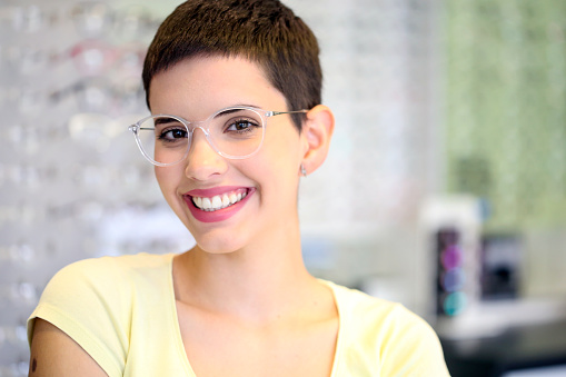 Young woman wearing transparent eyeglasses in an eyewear store. About 25 years old, Caucasian female.