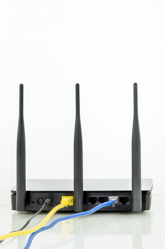 Wireless router with three antennas and cables connected. White background.