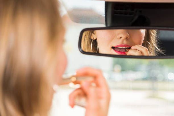 istock Blonde in car puts makeup on and looks in mirror 1217398304