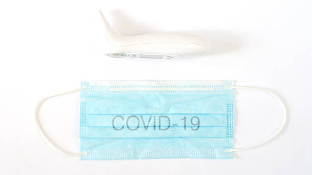 istock Surgical protective mask with Covid-19 sign and a termomether 1217400456