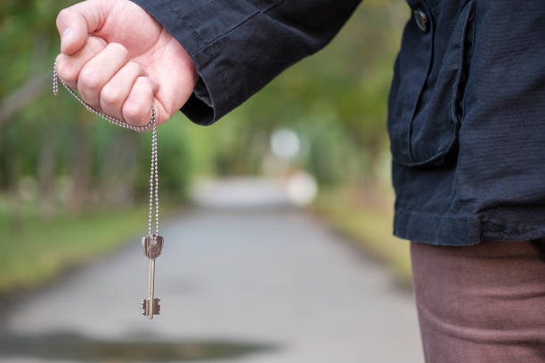 istock a man in a black jacket holds in his hand a chain on which hangs a key 1217404613