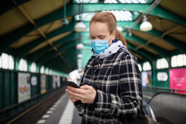 istock Woman with face mask texting on home at train station 1217404628
