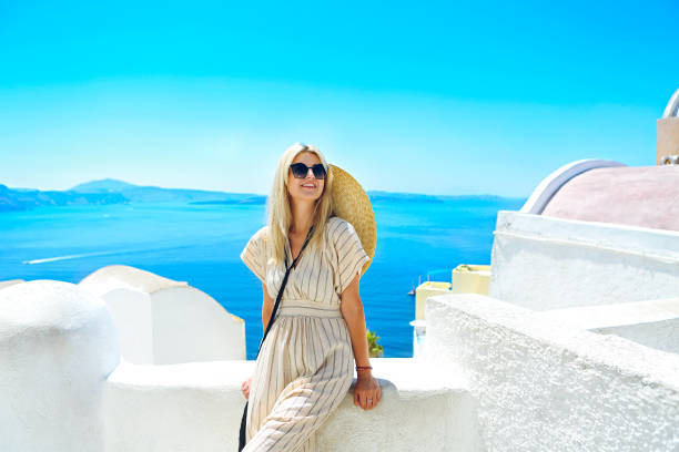 młoda kobieta w białej sukni i słomianym kapeluszu, spacerując po mieście oia, wyspa santorini, grecja - hat oia europe vacations zdjęcia i obrazy z banku zdjęć