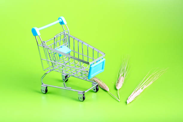 on a green background an empty cart from the store next to it are ears of rye