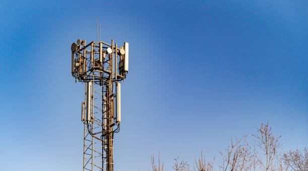 Communications, cell, mobile tower in UK set against a bright blue sky with copy space Wide shot of mobile cellular transmission tower set against a bright blue sky in the late afternoon web radio stock pictures, royalty-free photos & images