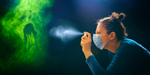 Killing coronavirus Masked woman spraying with antiseptic spray on green monster enemy coronavirus covid-19. destroyer photos stock pictures, royalty-free photos & images