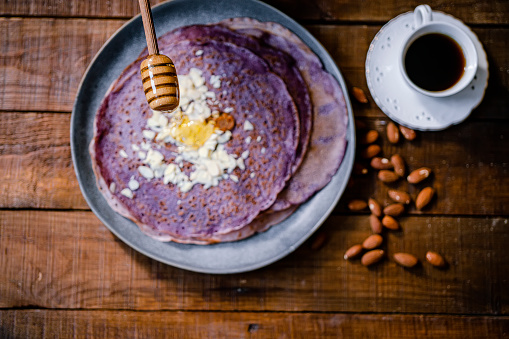 Thin purple crepes with honey, chopped almond and coffee