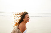Laughing mature woman walking on a beach on a breezy afternoon