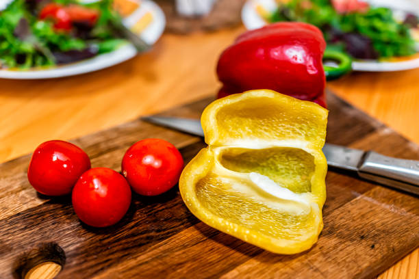 vue de plan rapproché de légumes de coupe sur la table de coupe avec deux plaques de salade végétalienne fraîche avec des poivrons jaunes rouges et des tomates - 18636 photos et images de collection