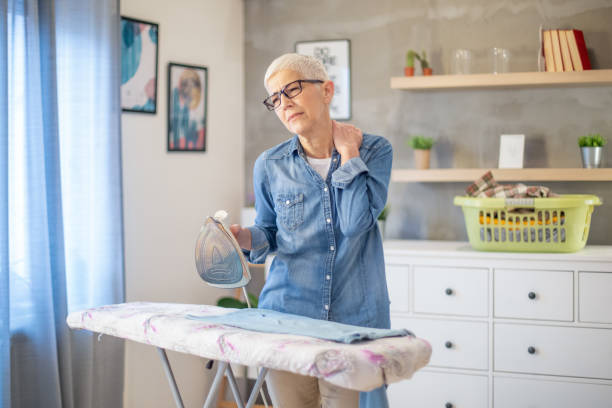 istock Beautiful senior woman multitasking on smart phone while doing the ironing during pandemic Covid-19 . Corona virus. 1217412737