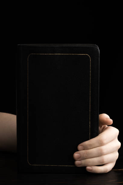 istock female hands holding a Bible on a dark background 1217413578
