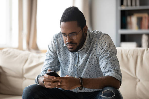 istock African American man sit on couch using smartphone 1217413686