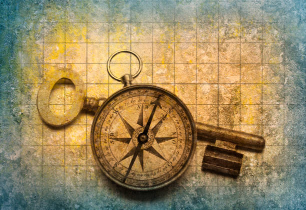 compass and gold key on an old map - the way forward compass rose map key imagens e fotografias de stock