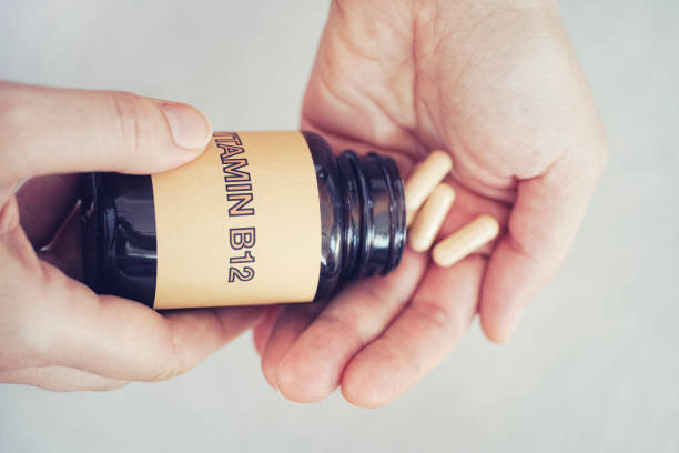 человек вынося витамин b12 таблетки из бутылки - поражение стоковые фото и изображения