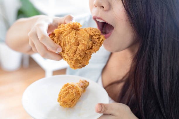 istock Girl holding fried chicken drumstick. 1217414983