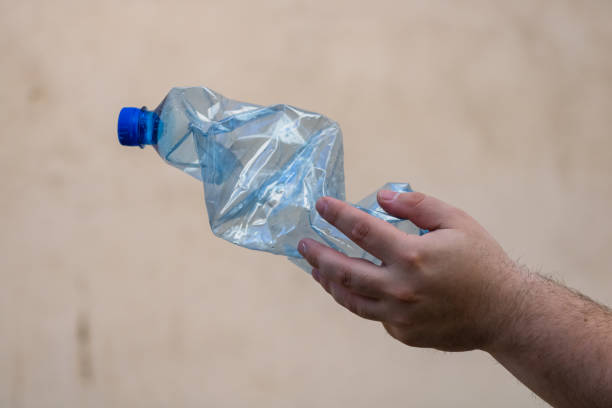 istock Hand holding smashed empty plastic bottle isolated on a blurred background. Recycle and volunteer concept. Environmental pollution and worldwide ecological problem 1217415671