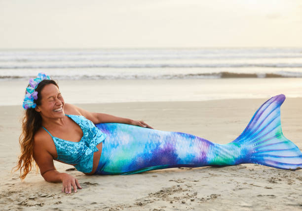 skrattande mogen kvinna klädd som en sjöjungfru på en strand - mature woman having fish bildbanksfoton och bilder