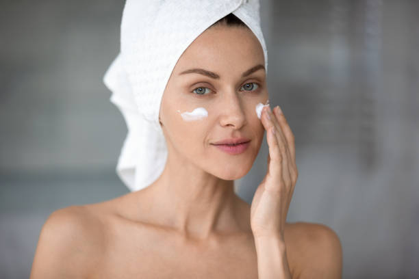 istock Peaceful young lady applying hydrating moisturizing creme. 1217416443